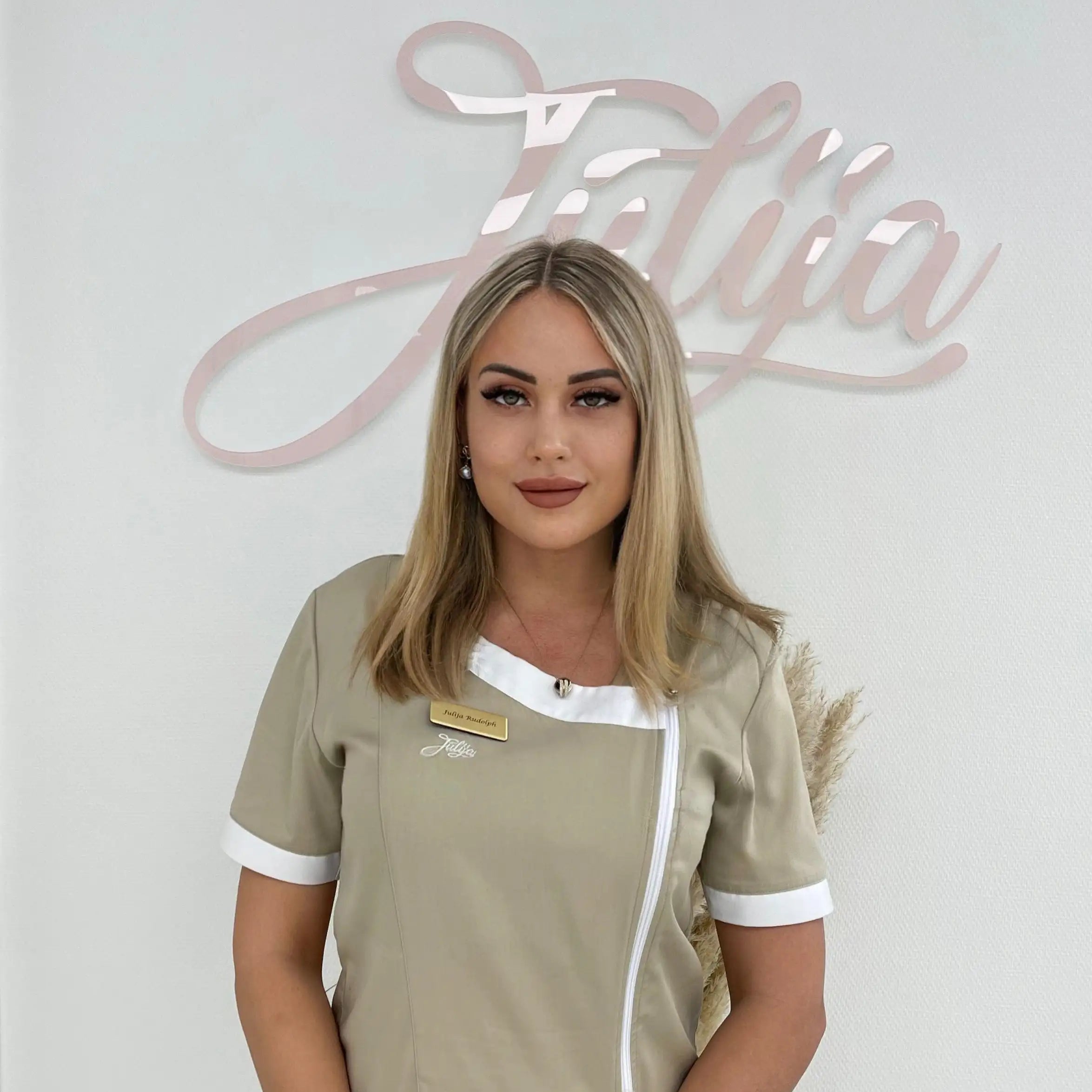 Julija steht vor dem Firmenlogo in Arbeitskleidung